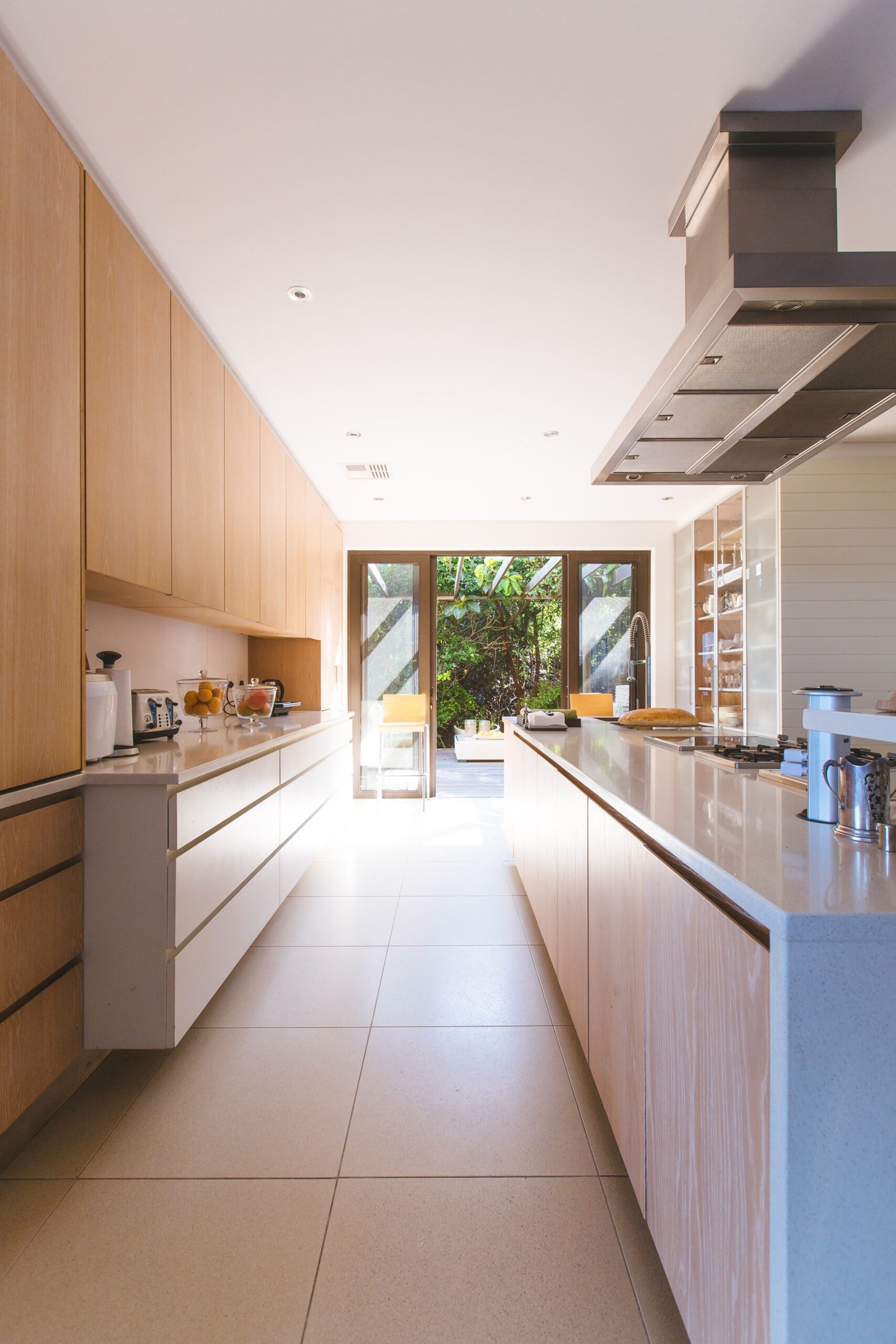 Long modern kitchen leading to open glass patio doors