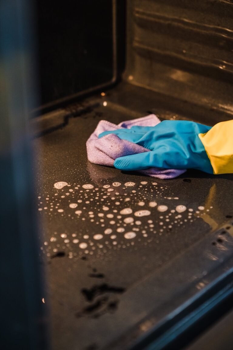 Gloved hands wiping the inside of an oven