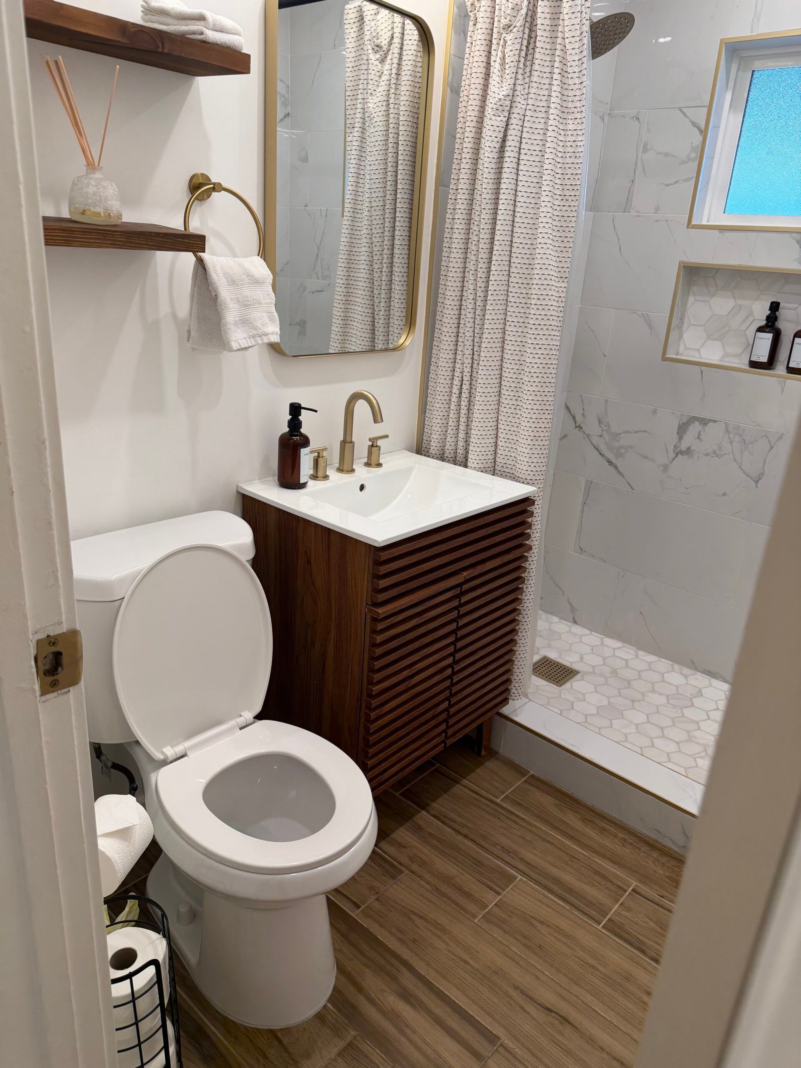 Elegant clean bathroom vanity and shower area with gold fixtures