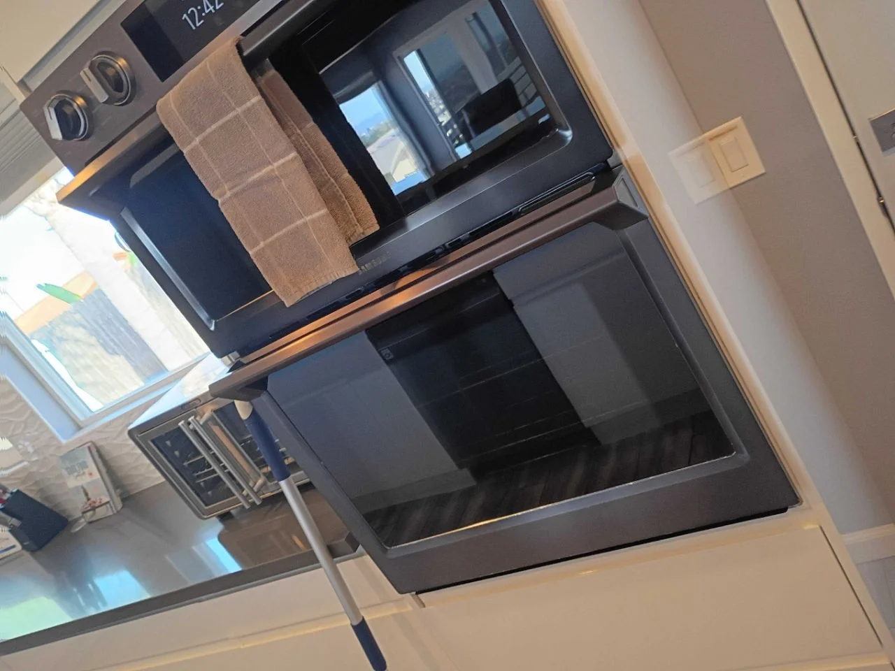 Built-in wall oven and microwave combo with a clean towel hanging on the handle