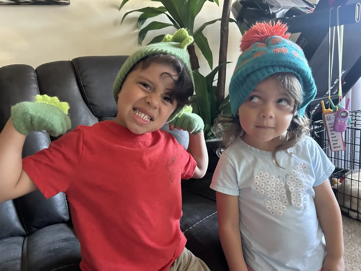 Two young children in knit hats making playful faces together