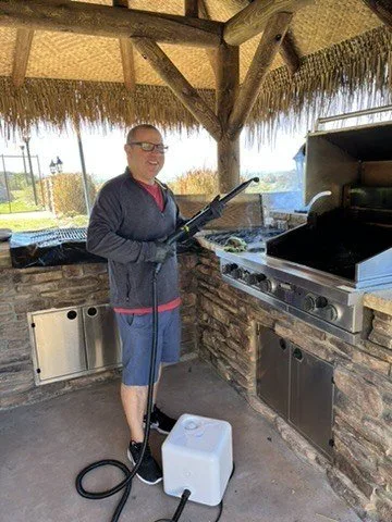 Paul steam-cleaning an outdoor kitchen grill during early side-job cleaning work