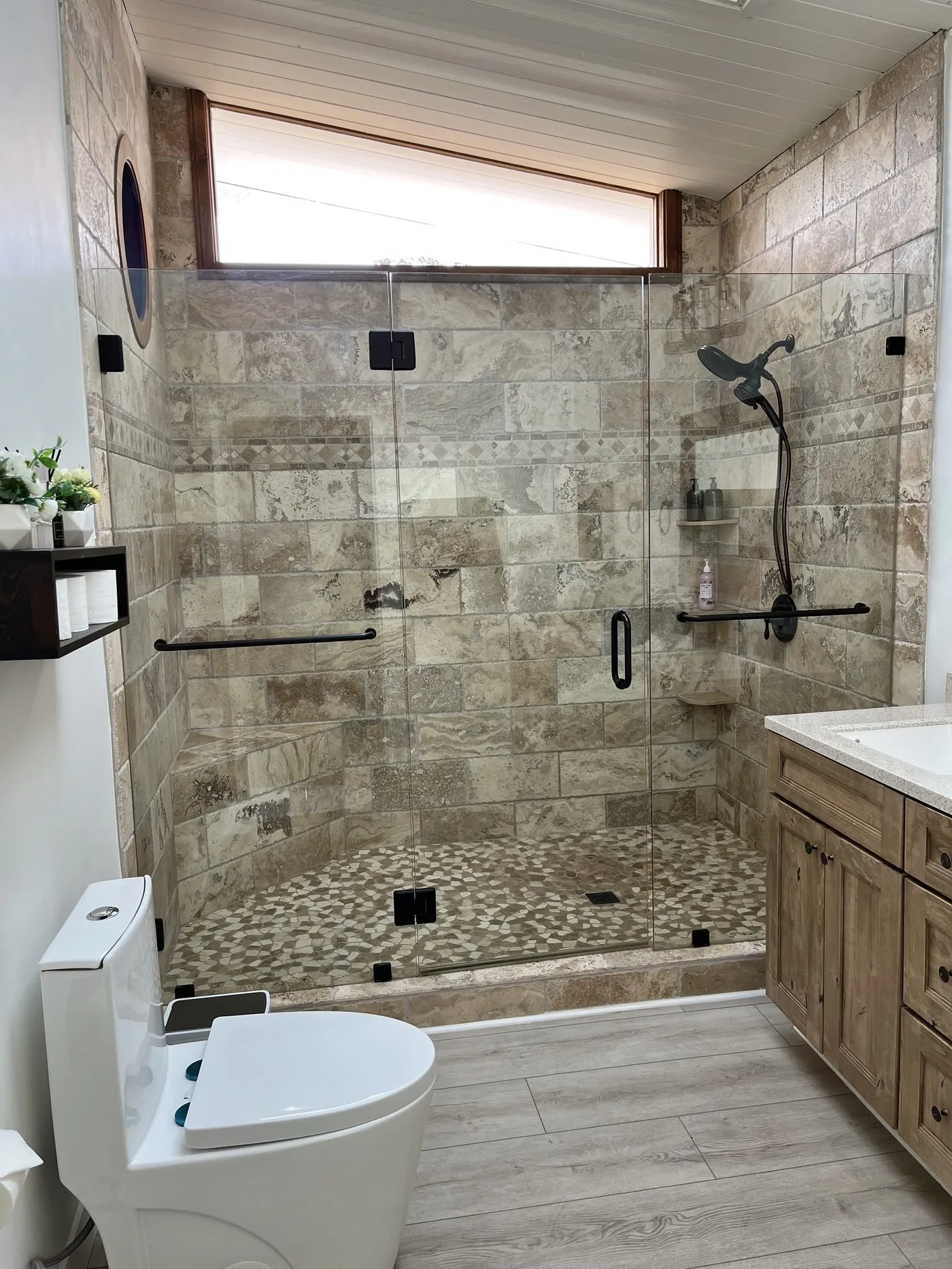 A finished large stone-tile walk-in shower with glass doors