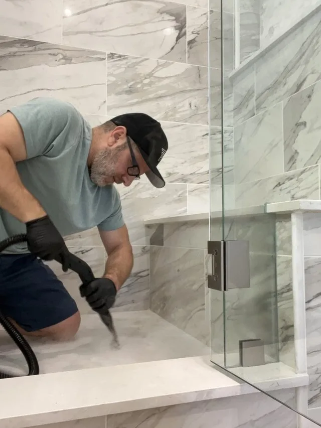 Paul steam-cleaning a marble shower floor during early side-job cleaning work