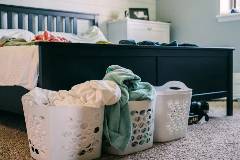 Cluttered bedroom with laundry baskets illustrating a home in need of a Suddenly Clean cleaning service
