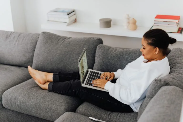 Customer relaxed on a couch booking a house cleaning service online with a laptop