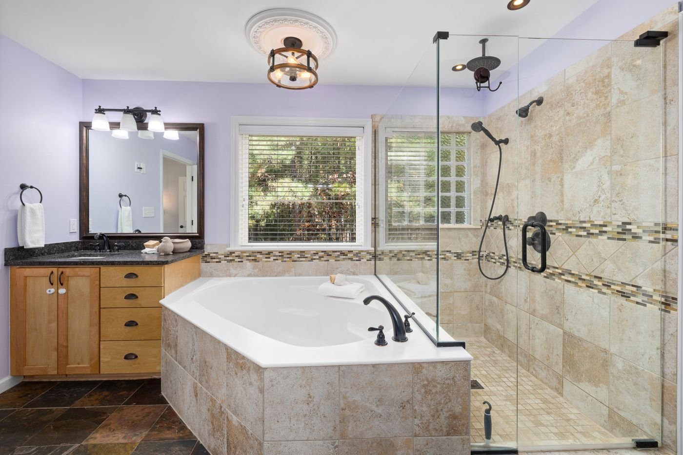 Bathroom with a tiled tub, glass shower and vanity