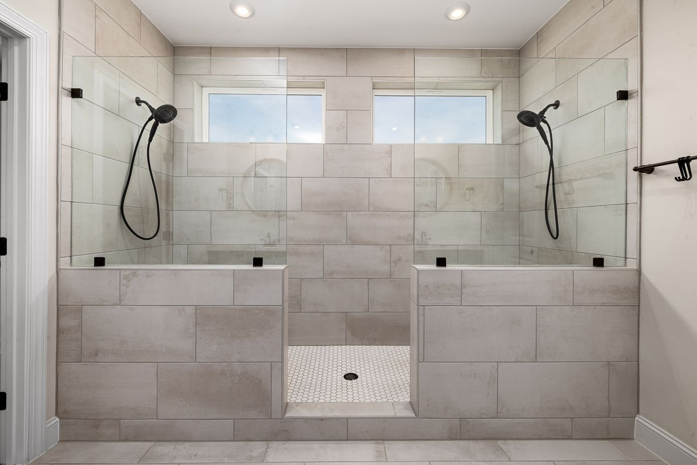 Large double walk-in shower with tile walls and a glass panel