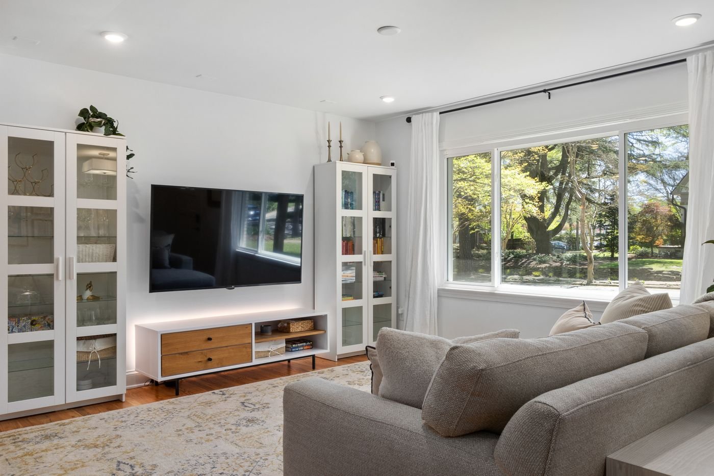 Living room with large window, sofa and display cabinets