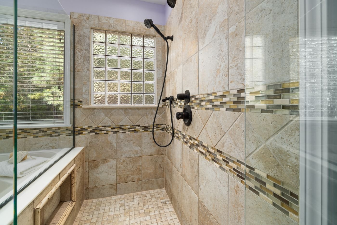 Tiled shower with a mosaic accent band and glass block window