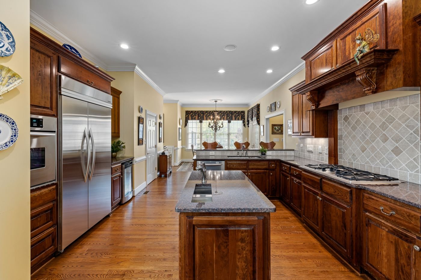 Long wood kitchen with a range hood over the cooktop and a center island